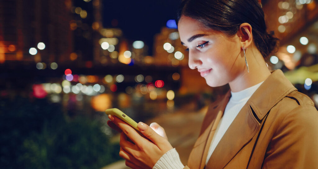 Una mujer joven consulta su teléfono móvil en la calle.