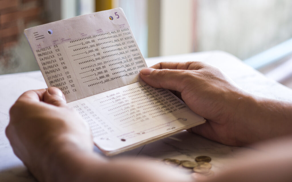 Una persona consulta su historial de movimientos bancarios en una libreta.
