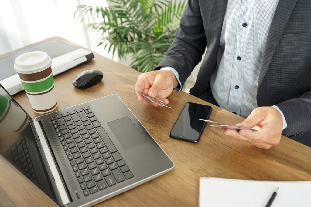 Un ejecutivo consulta sus tarjetas bancarias frente a su ordenador portátil.
