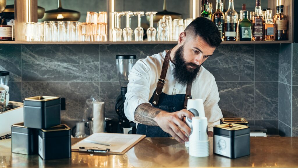 Camarero realiza inventario de sus productos tras la barra del bar.