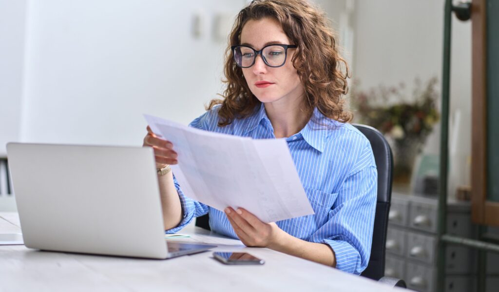 Una empleada consulta unos documentos en su escritorio.