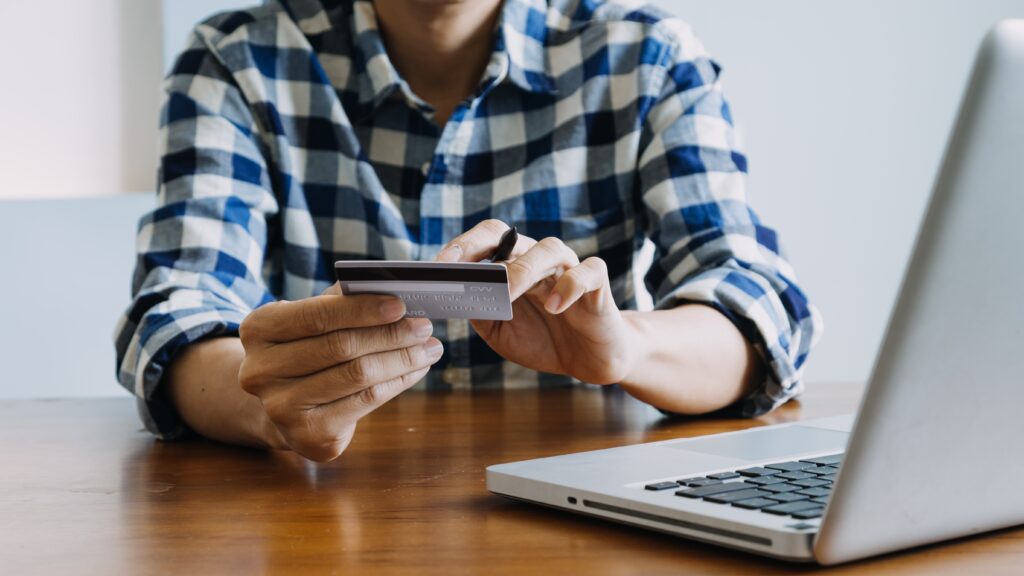 Una persona consulta su tarjeta bancaria frente a su ordenador.