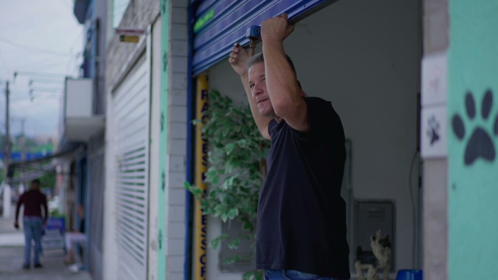 El dueño de un negocio abre la persiana de su local.