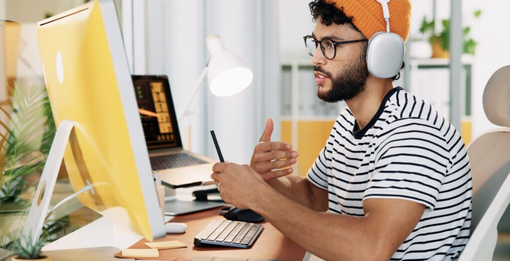 Un desarrollador web mantiene una videollamada de trabajo frente a su ordenador.