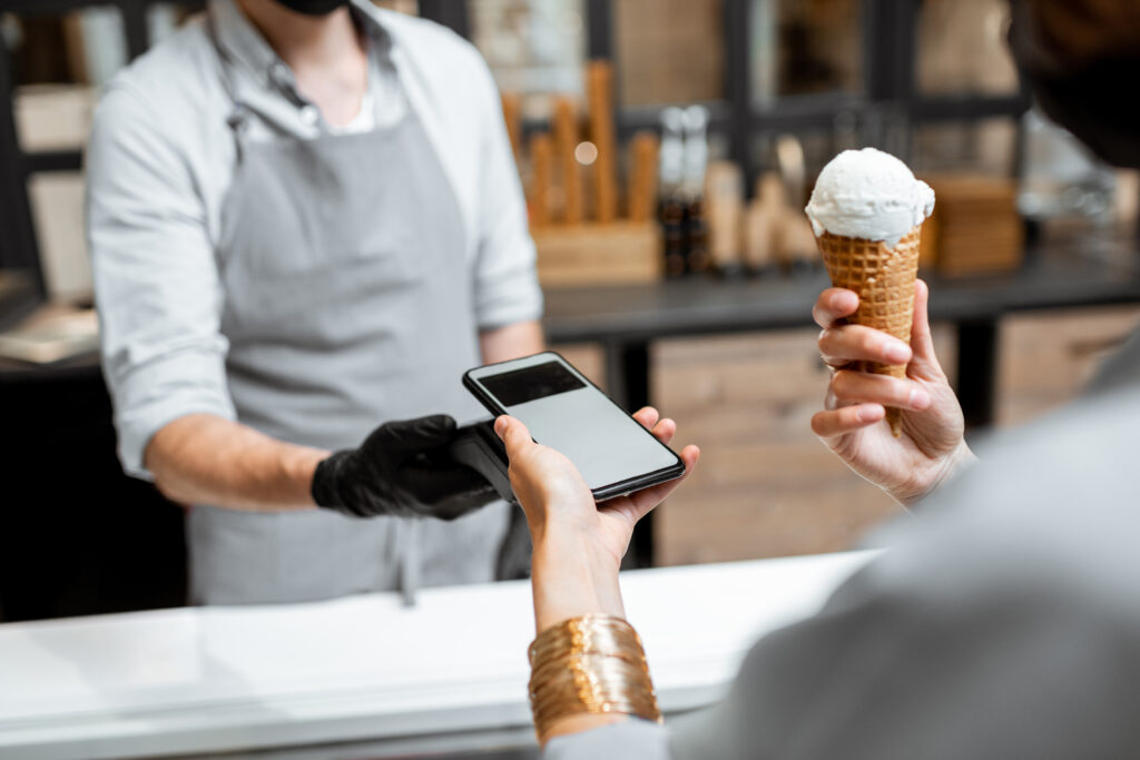 Una clienta paga su helado mediante pago contactless con su teléfono móvil.