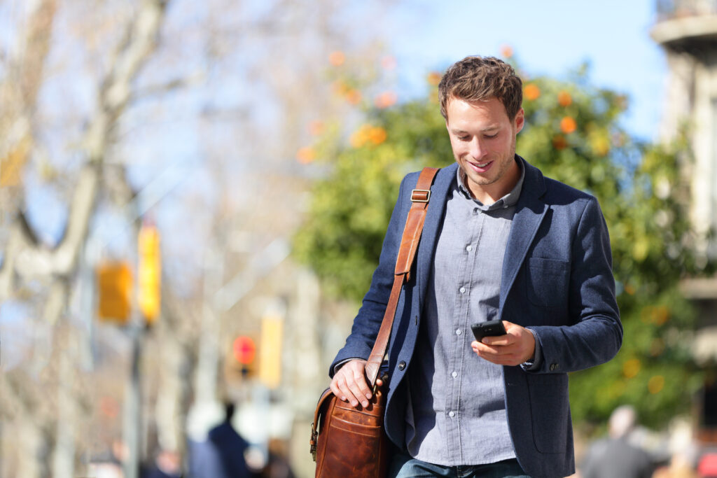 Un hombre consulta su teléfono móvil por la calle.